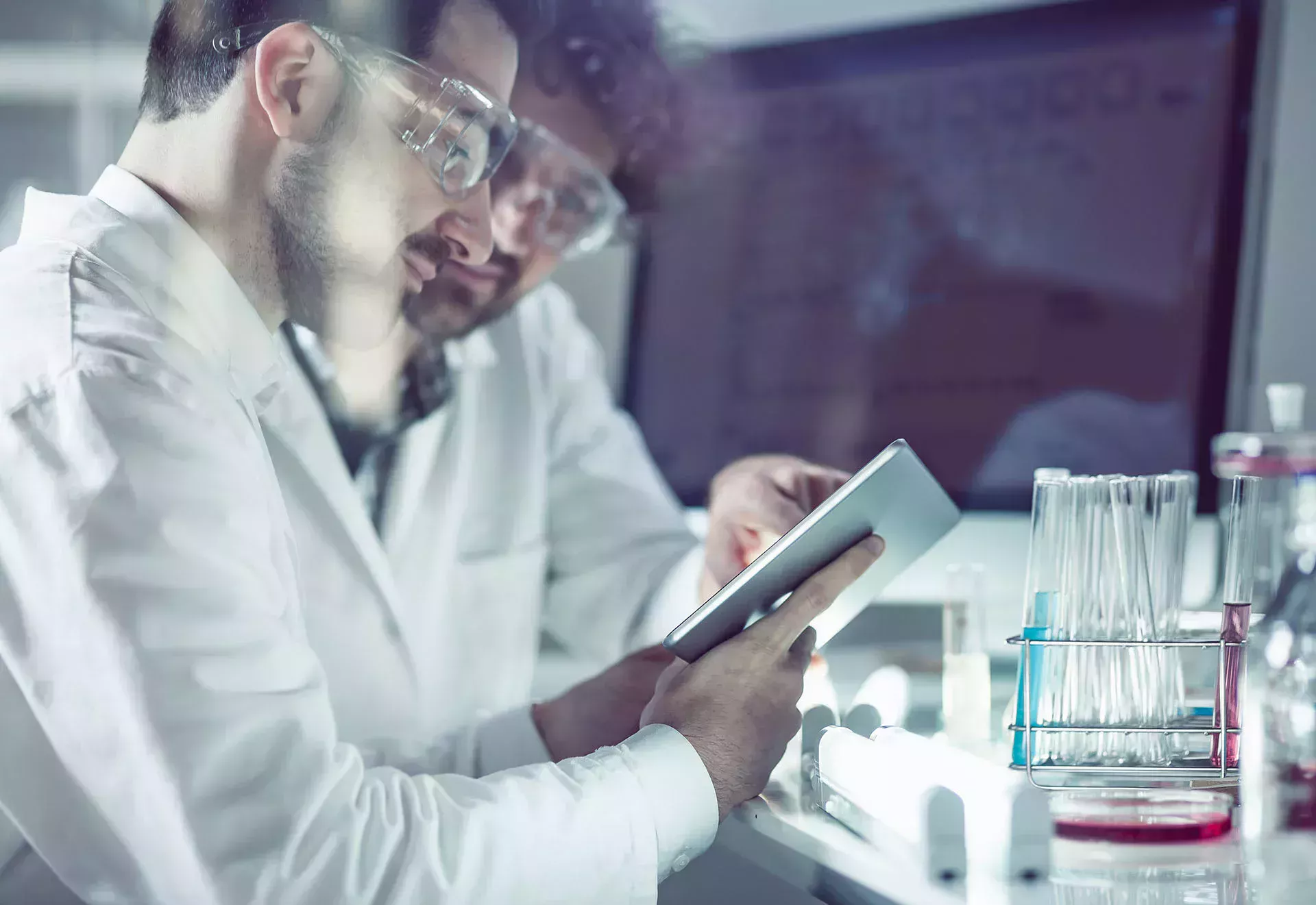 两名化学技术人员在实验室里查看平板电脑